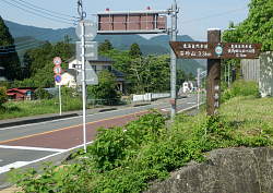 県道を渡った場所の標識、バス亭 0.1qとある